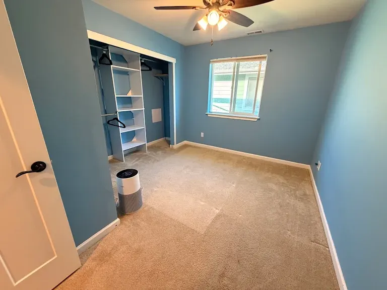 Clean beige carpet in an empty blue bedroom with an air purifier running