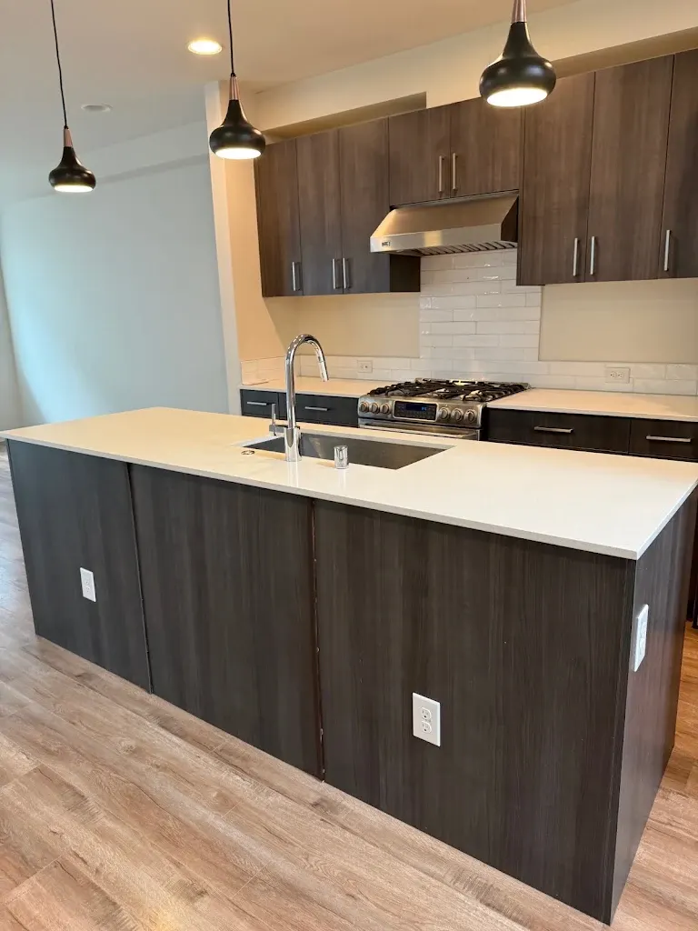 Townhome kitchen with dark island and light wood floor after turnover
