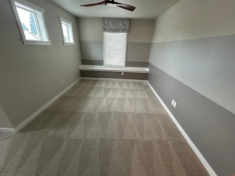 Clean gray-beige carpet with extraction wand pattern in an empty bedroom with a window seat